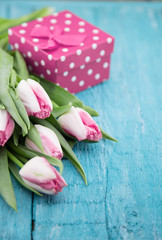 Wall Mural - Bouquet of Tulips and gift box on turquoise rustic wooden background with copy space for message. Spring flowers. Greeting card for Valentine's Day, Woman's Day and Mother's Day holidays. Soft focus.