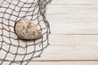 Fishing net with seashell on wooden background