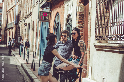 Fotografia Trois jeunes personnes discutent dans la rue, paysage urbain