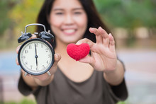 Giving Love And Time In Valentine's Day. Asian Women Hand Show Red Heart And Clock Times At 6 O'clock, It's Time To Loving Together.