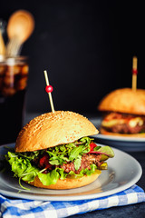 Wall Mural - Fresh homemade hamburger  in grey plate, over wooden table with dark background