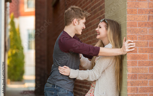 Fotografía Young couple talking and embracing against a wall.