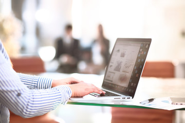 Happy business woman working a modern laptop computer with his team in background