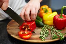 Chef Cutting Red Pepper On Wooden Board