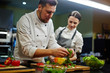 © pressmaster - Chef and his trainee cooking vegetable salad