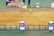 Sportswoman jumping into sandpit on triple jump competition in track and field championship