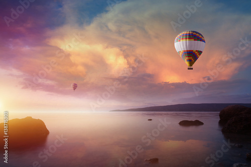 Fotografia, Obraz Two colorful hot air balloons flies in glowing sunset sky
