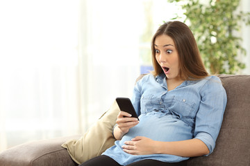 Wall Mural - Amazed pregnant woman looking at smart phone