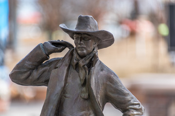 Closeup of a bronze cowboy from the Wild West times on a blurry background, USA. In color.