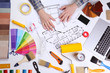 © Africa Studio - Decorator's hands on project drawing. Laptop, color swatches and tools on work table
