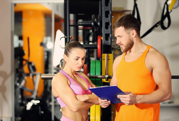 Wall Mural - Young woman with personal trainer in gym