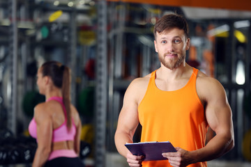 Canvas Print - Personal trainer holding clipboard with training plan in gym