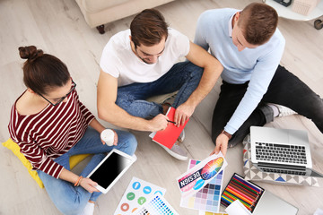 Poster - Three young designers sitting on floor of office room