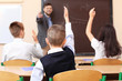 © Africa Studio - Pupils listening teacher and raising hands to answer in classroom