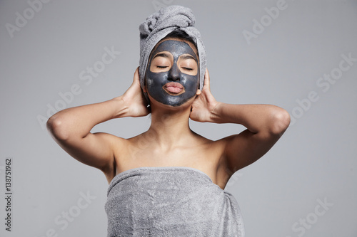 Fotografering mixed race woman with clay coal grey facial cleansing mask treatment