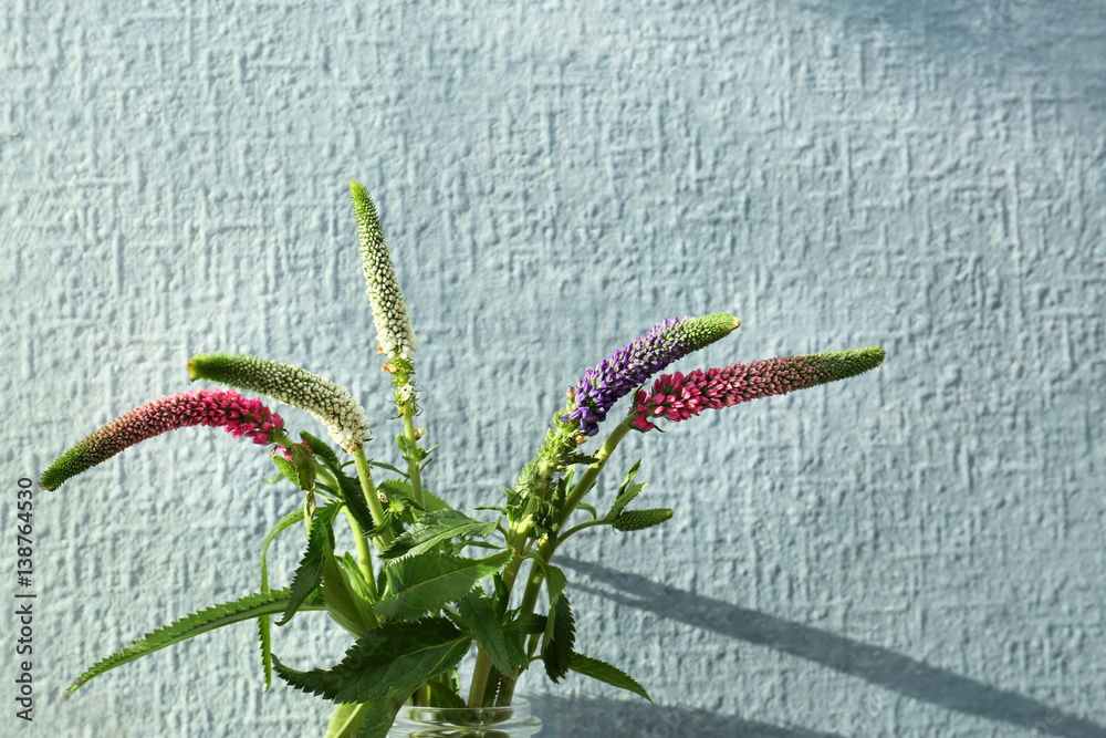 Beautiful flowers in glass vase on textured wall background
