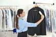 © Africa Studio - Woman with adhesive roller cleaning clothes in dry-cleaning salon