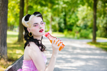 Portrait d'une jeune Pin'Up de profil buvant un soda, le regard vers l'objectif