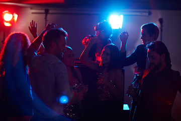 Canvas Print - Young stylish girls and guys enjoying disco party, dancing and drinking while famous DJ mixing music on background