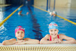 © pressmaster - Portrait of two schoolgirls smiling and looking at camera at pool swimming practice