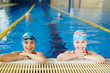 © pressmaster - Two schoolchildren smiling brightly looking at camera at border of clear blue water swimming pool