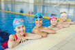 © pressmaster - Group of joyful school kids smiling looking to camera at border of swimming pool during practice