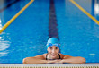 © pressmaster - Beautiful woman wearing goggles and cap smiling looking to camera at border of  swimming pool