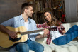 © LIGHTFIELD STUDIOS - Smiling young woman holding wine glass and looking at handsome man playing guitar