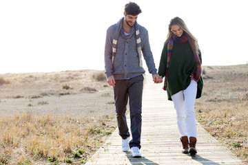 Beautiful young couple in love walking in a cold winter on the beach.