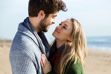 Beautiful young couple in love in a cold winter on the beach.