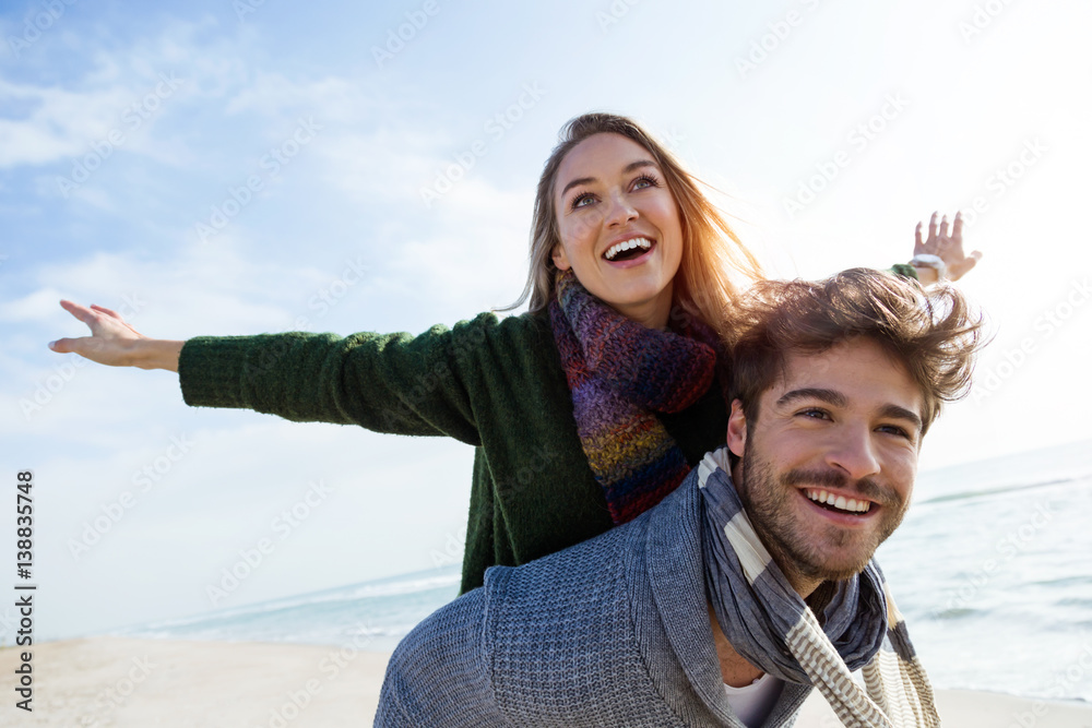 Happy young couple enjoying the day in a cold winter on the beach. - obrazy, fototapety, plakaty 