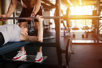 Personal trainer helping woman bench press