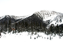 View Of Chalet Surrounded By Snow Covered Trees And Mountains