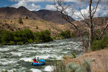 Two People Steering Dinghy On Rapids By Mountains