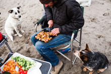 Man Slicing Vegetables, Two Dogs By His Side 