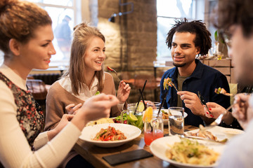 Canvas Print - happy friends eating and drinking at restaurant