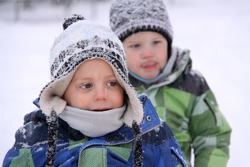 Two boys wearing stocking caps and warm jackets in snowfall