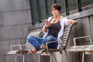 outdoor portrait of young happy smiling woman talking by cell phone in city, urban background