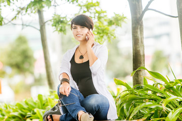 outdoor portrait of young happy smiling woman talking by cell phone in city, urban background