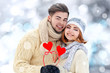 © Africa Studio - Young couple in love holding red paper hearts outdoors in winter