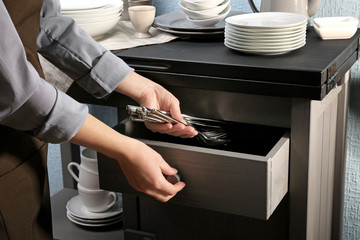 Sticker - Woman putting silverware into drawer, closeup