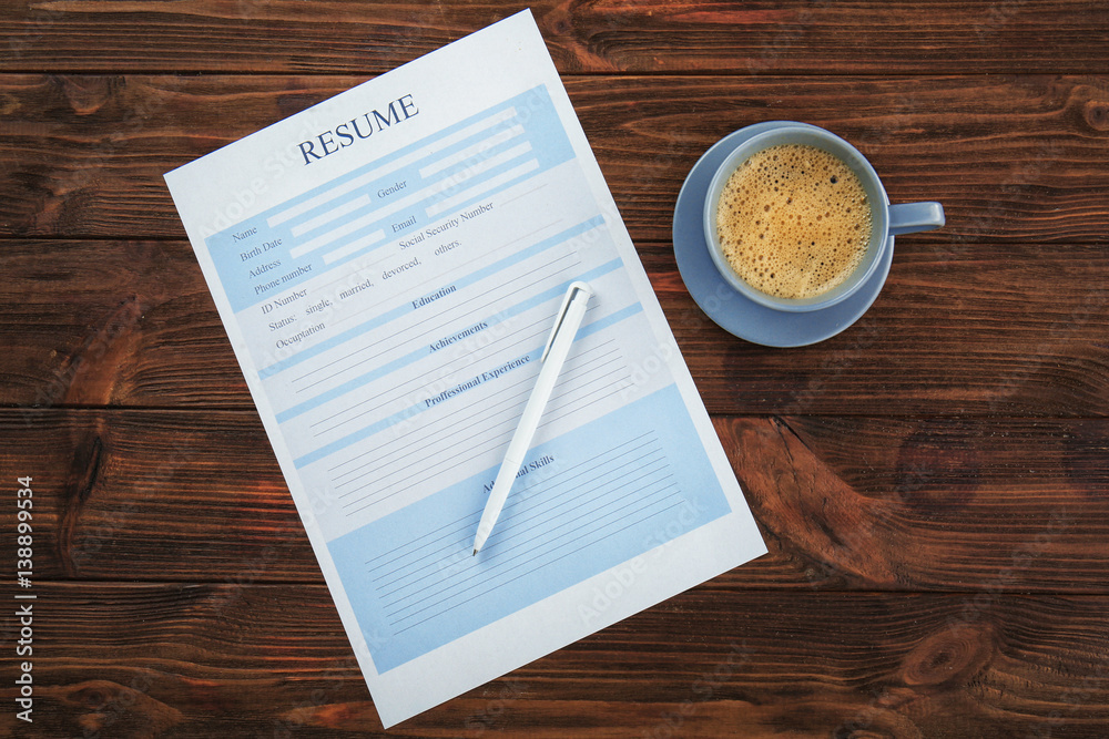 Resume, pen and cup of coffee on wooden table