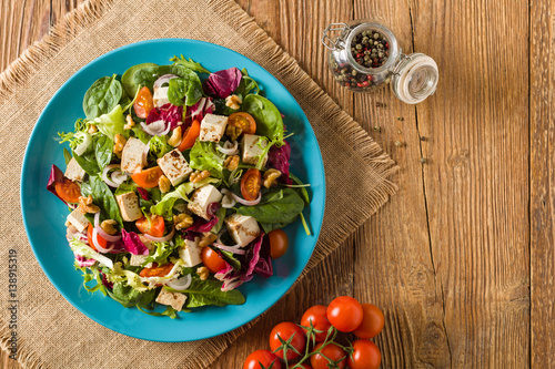 wysmienita-salatka-z-tofu-pomidorow-i-orzechow-wloskich-podana-na-niebieskim-talerzu