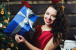 © myronovychoksana - Curly brunette woman holds blue present box