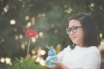 Canvas Print - Asian girl watering a red gerbera