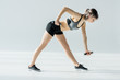 Side view of concentrated young sportswoman training with dumbbells