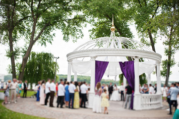 Crowd of people on wedding ceremony under white arch on island of love. Blured effect.