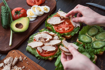 Poster - girl chef making sandwich in rustic style with turkey meat and chicken and vegetables