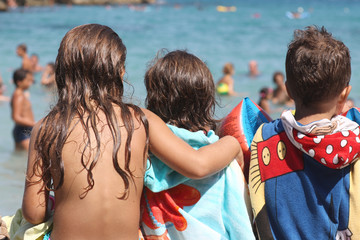 Children have a rest after swimming in the sea sitting on the beach.