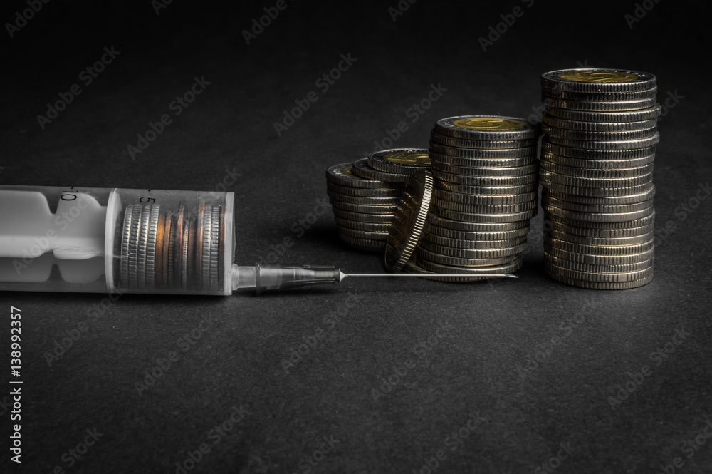 Cash injection with syringe to the coins stacks - business concept of a loan, credit or investment